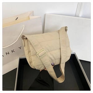 Gros plan du sac bandoulière matelassé beige avec coutures et sangle large