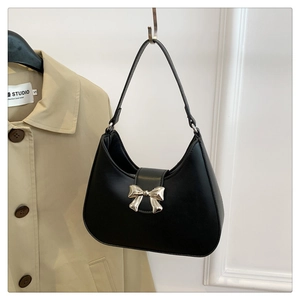 Detail of black faux leather crescent bag featuring a golden bow metal buckle
