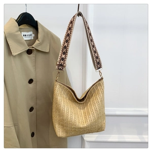 Close-up of woven straw tote bag with wide geometric pattern adjustable shoulder strap