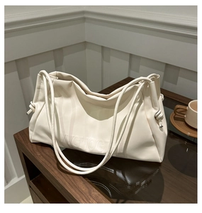 Detail of cream white leather tote bag with embossed letters on a vintage wood surface