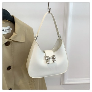 Detail of silver metallic bow buckle on white leather hobo bag with smooth texture