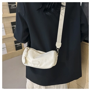 Minimalist cream white leather cylinder crossbody bag shown on a model in a modern room