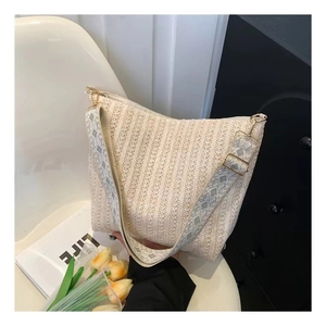 Detail of woven straw tote bag featuring a geometric jacquard strap and gold buckle