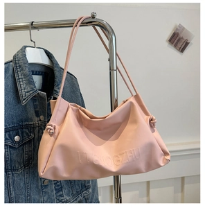 Close-up of pink tote bag featuring embossed lettering and side drawstring knot detail