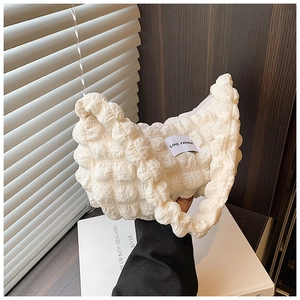 Detail of quilted bubble texture and fashion label on off-white shoulder handbag