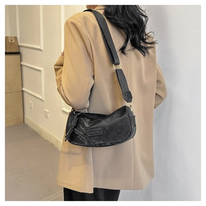 Detailed view of black retro hobo bag with a wide strap on a casual blazer outfit
