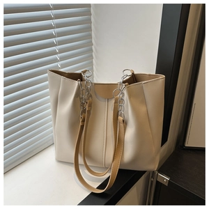 Detail of the cream PU leather tote bag with pleated sides and chain strap outdoors
