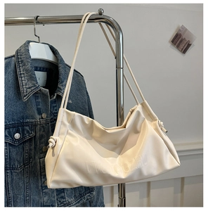Detail of cream white tote bag featuring embossed lettering and soft pleated texture