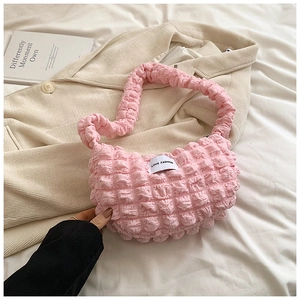 Detailed close-up of pink bubble pleated fabric texture and brand label on shoulder bag
