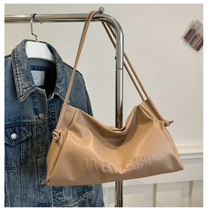 Close-up of light brown tote bag featuring VVGNOGZHU embossed letters and knot detail