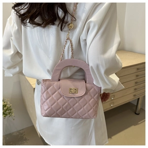 Detail of pink quilted crossbody bag with golden twist lock and metal chain strap