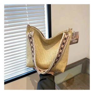 Close-up of handwoven straw tote bag with ethnic style jacquard wide shoulder strap