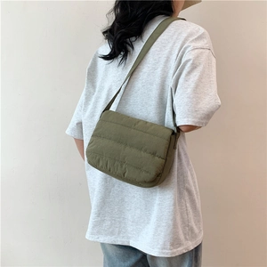 Sac bandoulière en nylon matelassé vert armée porté par un mannequin au style décontracté