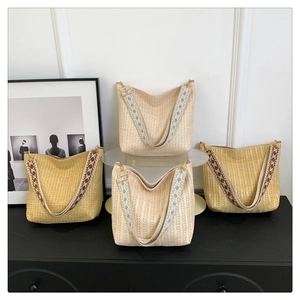 Detail of woven straw tote bags with patterned ethnic style wide shoulder straps