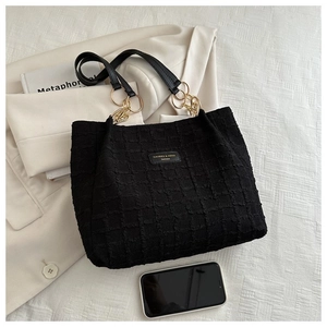 Detail of black tote bag featuring textured bubble fabric and gold chain hardware accents