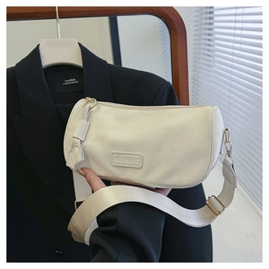 Detail of off-white canvas crossbody bag with wide strap and fashion logo tag