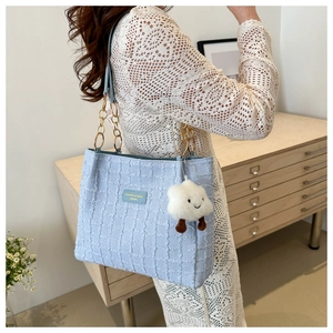 Detail of light blue textured tote bag with golden ring chain and plush cloud charm