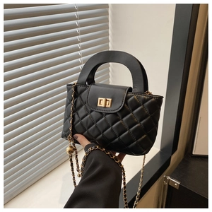 Detail of black quilted faux leather crossbody bag with gold chain strap and metal lock