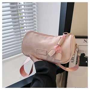 Detailed view of pink crossbody cylinder bag with wide strap and fashion leather tag