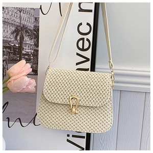 Detailed view of the woven texture and golden horseshoe clasp on a beige straw bag