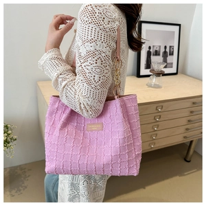 Detail of pink pleated tote bag with golden chain strap and leather fashion label
