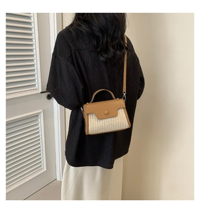 Detail of a brown leather and straw patchwork crossbody bag worn over a black shirt