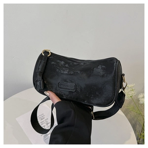 Detail of vintage black cylinder bag with wide strap and fashion leather patch