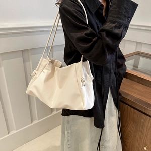 Elegant cream pleated tote bag with knot details and thin straps shown on a model