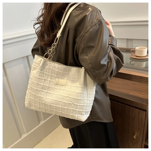 Detail of white pleated tote bag with gold chain strap shown in a vintage interior setting