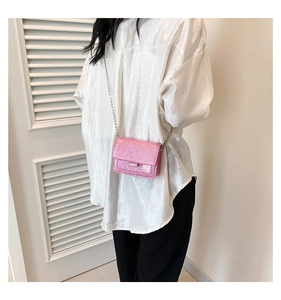 Détail d'un mini sac bandoulière rose à paillettes avec chaîne argentée sur chemise