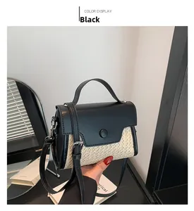 Detail view of the black flap and woven straw texture on the stylish crossbody bag