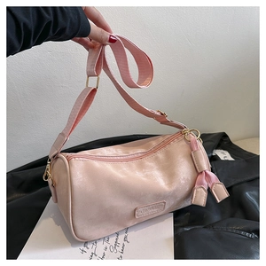 Detailed close-up of pink cylinder pillow bag with wide fabric strap and gold buckle