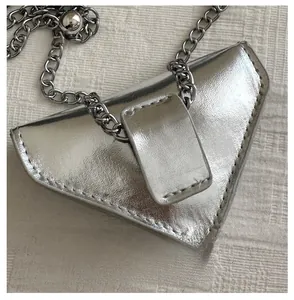 Détail du mini sac triangulaire argenté montrant le cuir métallisé et les coutures fines
