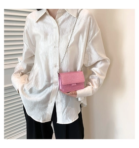 Mini sac bandoulière rose à paillettes avec chaîne argentée sur une chemise en satin
