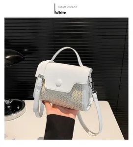 Detail of white woven straw crossbody bag with smooth leather flap and handle accents