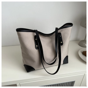 Detalle del bolso tote de lona beige con adornos de cuero negro y refuerzo en las esquinas
