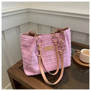 Detail of pink waffle texture tote bag with leather logo patch on a wooden table