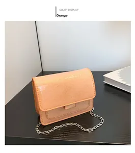 Détail d'un mini sac à rabat brillant orange avec une bandoulière en chaîne argentée