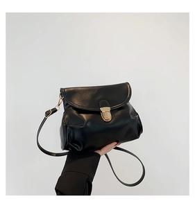 Detailed close-up of a black crossbody bag featuring a golden rotating metal lock