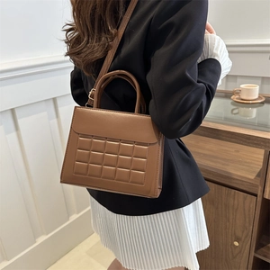 Borsa a mano trapuntata marrone con motivo a nido d'ape indossata da una modella