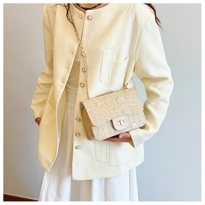 Close-up of beige straw saddle bag with floral embroidery and gold metal clasp