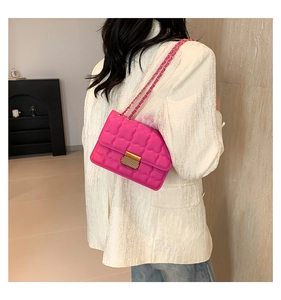 Chic bright pink quilted chain bag with gold lock shown on a white blazer outfit