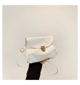 Detail of white glossy faux leather shoulder bag featuring a golden metal twist lock