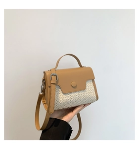 Detail of small woven crossbody bag with brown faux leather trim and silver metal hardware