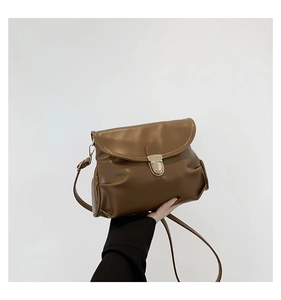 Close-up of pleated soft PU leather brown shoulder bag with golden metallic lock