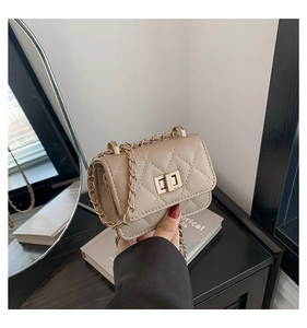 Detail of beige quilted crossbody bag with gold chain strap and metallic twist lock clasp