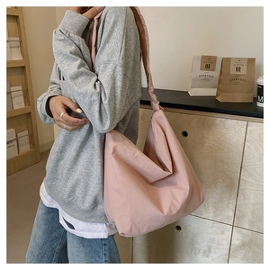 Detailed side view of large Morandi pink nylon crossbody bag worn by a model