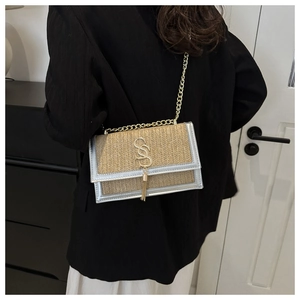 Detail of woven straw crossbody bag with silver leather trim and gold chain strap