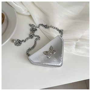 Close-up of silver triangular mini bag with metallic bow detail and chain strap