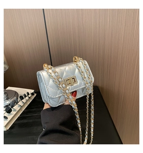 Close-up of silver quilted crossbody bag featuring gold turn-lock and chain strap